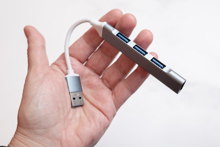 Port Multi Splitter Adapter USB hub for connecting additional equipment to laptop. Additional USB ports in a metal case on a short wire. Demonstration of the product in the palm of your hand.の写真素材