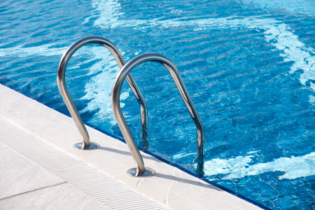 A Stainless still ladder for descending into the pool. Modern swimming pool with ladder at resortの写真素材