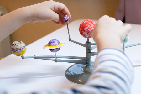 Preschooler child is making a solar system project. A child makes a craft on the subject of astronomy. Education and development of children.の写真素材