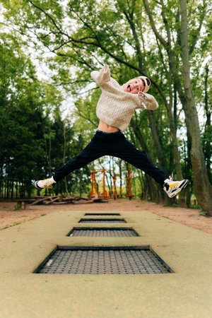 Teen boy jumping over several trampolines on a sports groundの写真素材
