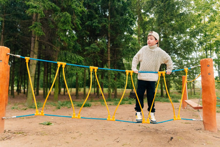 Teen boy playing in a rope town on the playground, obstacles