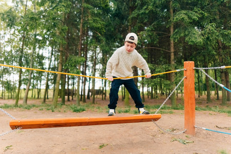 A teenage boy overcomes obstacles in a rope town on the playgroundの写真素材