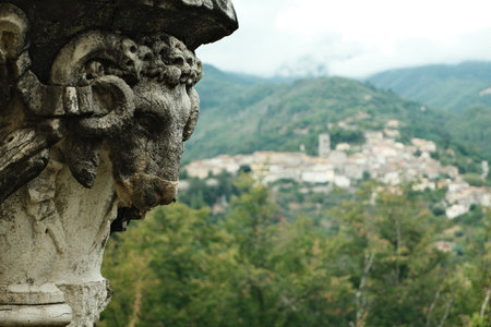 Scenic view of a historic village captured near an ornate stone sculpture in the mountainsの写真素材