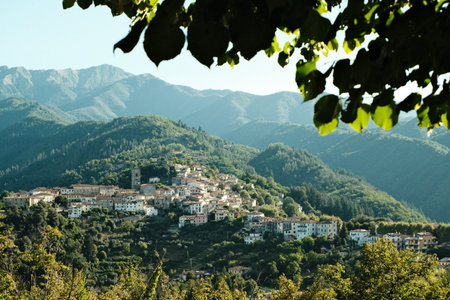 Mountain village nestled in green hills on a sunny day with clear skiesの写真素材