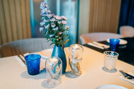 Elegant dining table setting with flowers and candles in a modern restaurant interiorの写真素材