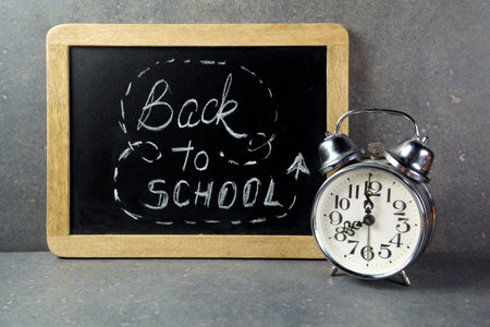 Vintage alarm clock with blackboard. Back to school