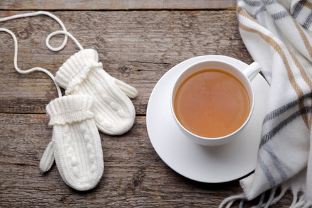 Cup of tea with gloves on wooden background
