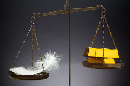 The feather outweighs a stacks of golden bars on the scaleの写真素材