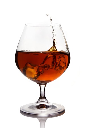 Splash of cognac in glass isolated on whiteの写真素材