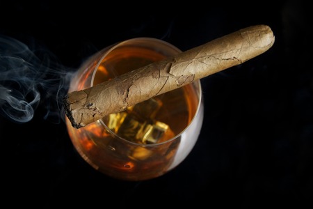 Snifter glass of cognac and cigar on blackの写真素材
