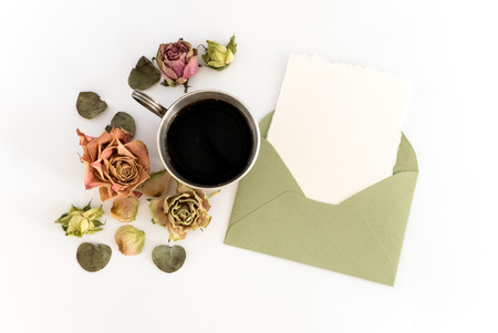 Cup of coffee, blank paper in the envelope, pen and flowers. flat layの写真素材