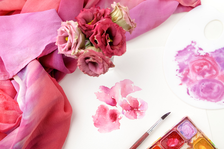 Workspace. flowers painted with watercolor and paintbrush on white background. Overhead view.の写真素材