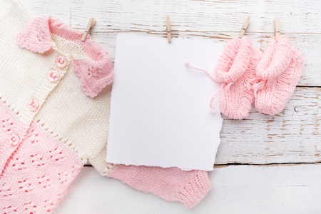 Baby girl clothes with blank card on wooden background. Flat lay. Owerhad viewの写真素材