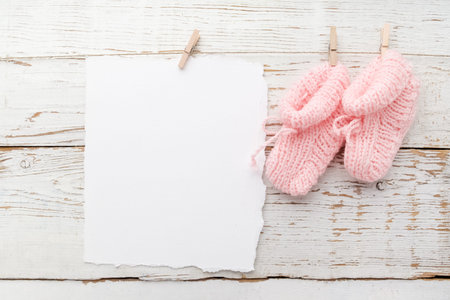 pink baby's booties. Small girls sock, blank card on white wooden backgroundの写真素材