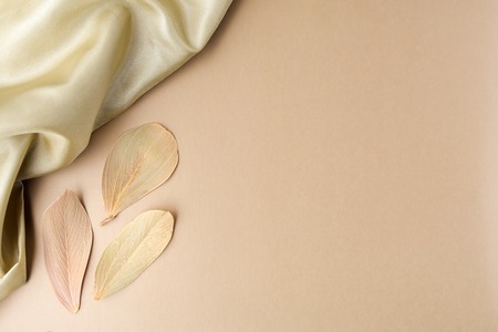 Satin on golden background with leaves. Flat lay. Owerhad viewの写真素材