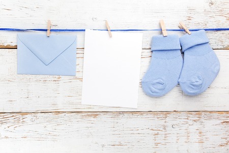 Small boy blue socks, blank card and evelop on white wooden background. Flat lay.の写真素材