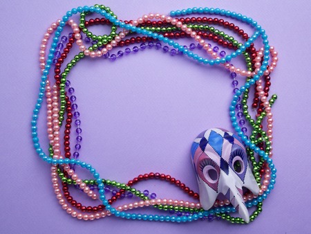 Mardi Gras beads and mask making a frame with copy space on purple background.Flat lay. Top viewの写真素材