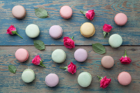 Macarons flat lay withroses and leaves on green wooden background. Top viewの写真素材
