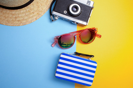Summer holiday concept, Travel Concept with bag, camera and hat on blue and yellow background.の写真素材