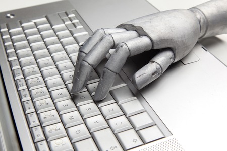 Futuristic robot hand typing and working with laptop keyboard. Mechanical arm with computerの写真素材