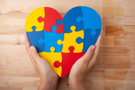 World Autism Awareness day, mental health care concept with puzzle or jigsaw pattern on heart with childs handsの写真素材