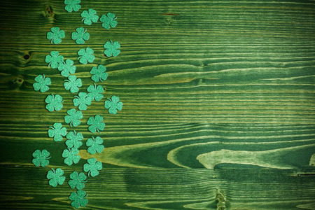 St Patricks Day side border of glitter paper shamrocks on green wood backgroundの写真素材