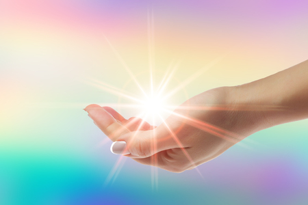 Healing hands with bright sunburst on rainbow backgroundの写真素材