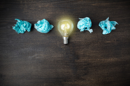 great idea concept with crumpled light blue paper and light bulb on wooden backgroundの写真素材