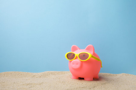 Piggy bank with sunglasses on the beachの写真素材
