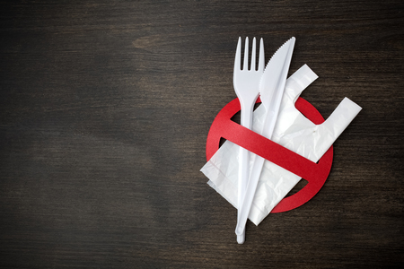 White plastic tableware on a wooden background as a symbol of environmental pollution. Ban single use plastic.の写真素材