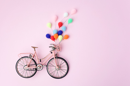 Colorful balloon hang the pink bicycle vintage on pink pastel background. idea of love. Minimal love concept.の写真素材