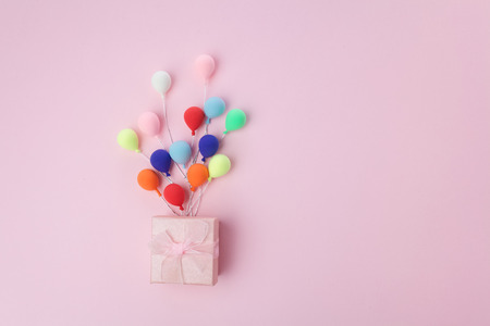 Pink gift box with colorful balloon on pink background. minimal holiday concept. Top viewの写真素材
