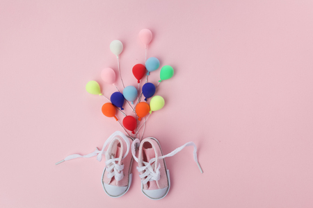 Pink baby shoes with colorful balloon on pink background. minimal hollyday concept.の写真素材