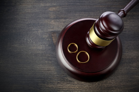 Wedding rings hammer of a judge on a dark wooden background. Divorce proceedingsの写真素材