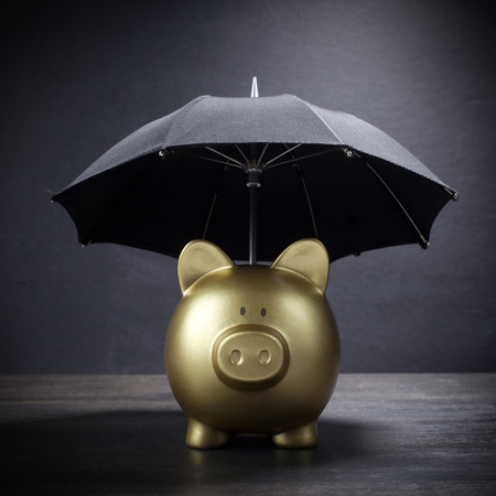 Gold Piggy bank with umbrella concept for finance insurance, protection, safe investment or bankingの写真素材