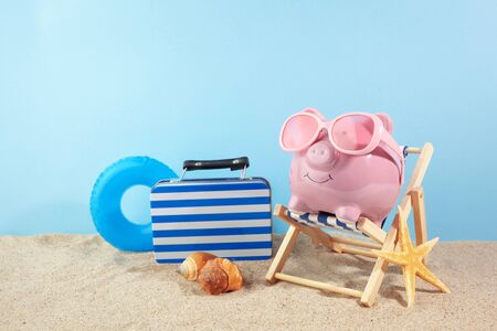 Pink piggy bank with sunglasses on the beachの写真素材