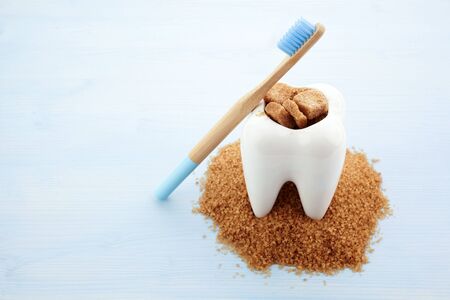 Ceramic tooth in big pile of brown sugar. Caries and sugar concept. Dental care conceptの写真素材