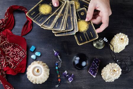 Fortune teller female hands and tarot cards on dark wooden table. Divination concept.の写真素材