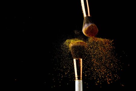 Cosmetic brush with golden powder spreading on black backgroundの写真素材