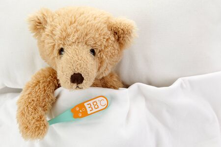 Teddy Bear is sick in bed on white backgroundの写真素材
