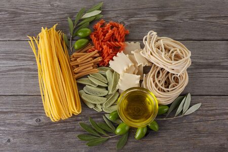 Different kinds of of pasta on the wooden background. Spaghetti. Olive oil.の写真素材