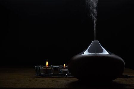 Aromatherapy. Essential oil aroma diffuser against dark background with copy space.