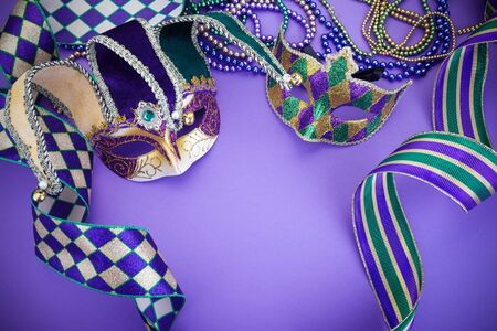 Colorful Mardi Gras mask on purple background with beads and ribbons. Top view. Copy spaceの写真素材