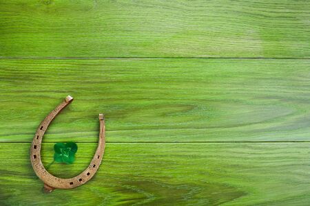 Horseshoe and clover on green wooden background. Green four leaf clover. Saint Patricks day symbol.の写真素材