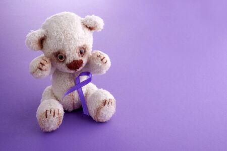 Epilepsy day. Health care concept. Teddy bear with purple ribbon on purple background. Epilepsy or Cancer hope.の写真素材