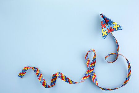 Autism awareness day or month. Paper plane in origami style with autism awareness puzzle ribbon on blue background.の写真素材