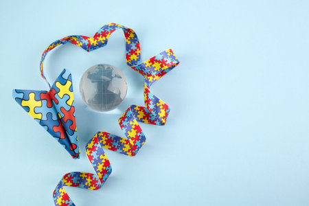 Autism awareness day or month. Paper plane in origami style with autism awareness puzzle ribbon on...