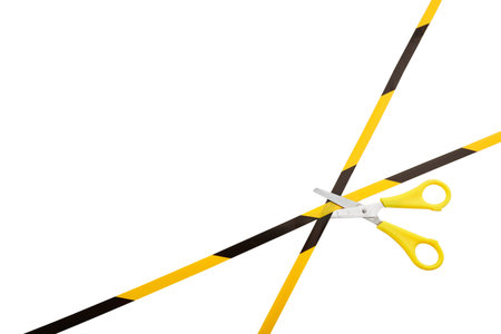 End of quarantine concept. Yellow and black warning stripes are cutting by scissors isolated on...