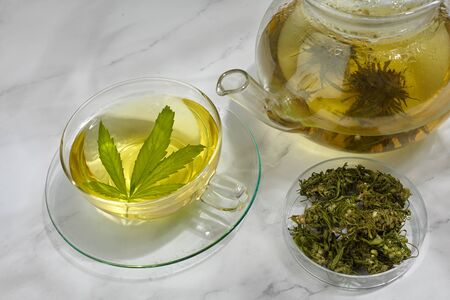 Cannabis herbal tea. Hot drink on light background with hemp leaves.の写真素材