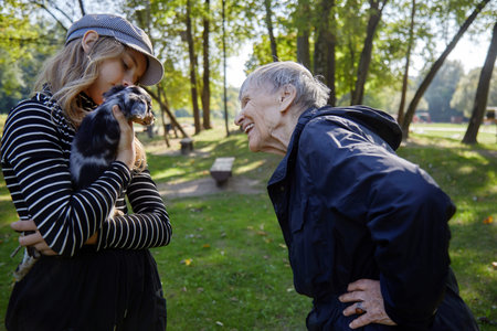 Senior women and girl playing with dog in park